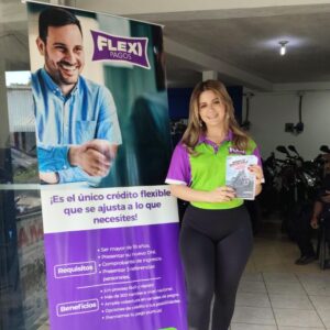 Promotora de Flexi Pagos junto a banner informativo de créditos flexibles durante una campaña promocional en Honduras