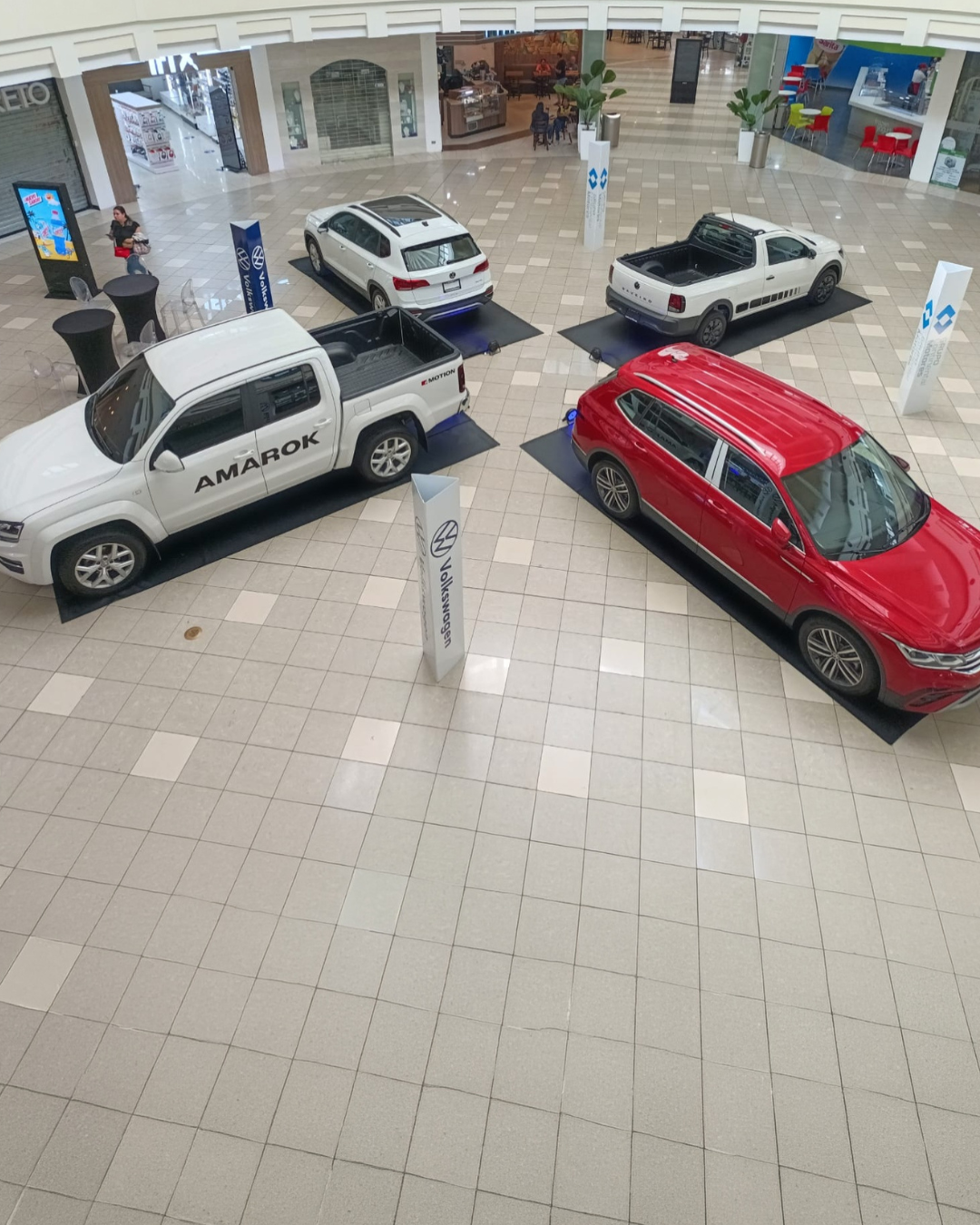 Exhibición de marca Volkswagen en espacio interior con vehículos en punto de exhibición comercial