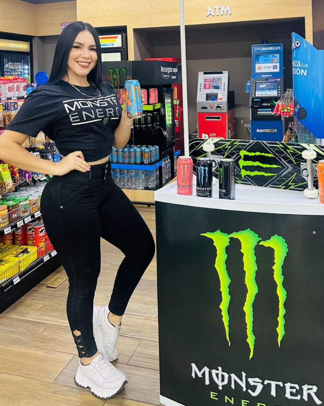 Edecán de marca Monster Energy en punto de degustación BTL con exhibición promocional en tienda.