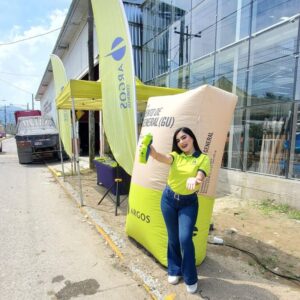 Promotora de Argos en evento BTL en Honduras junto a stand corporativo, banderola publicitaria y exhibición de marca