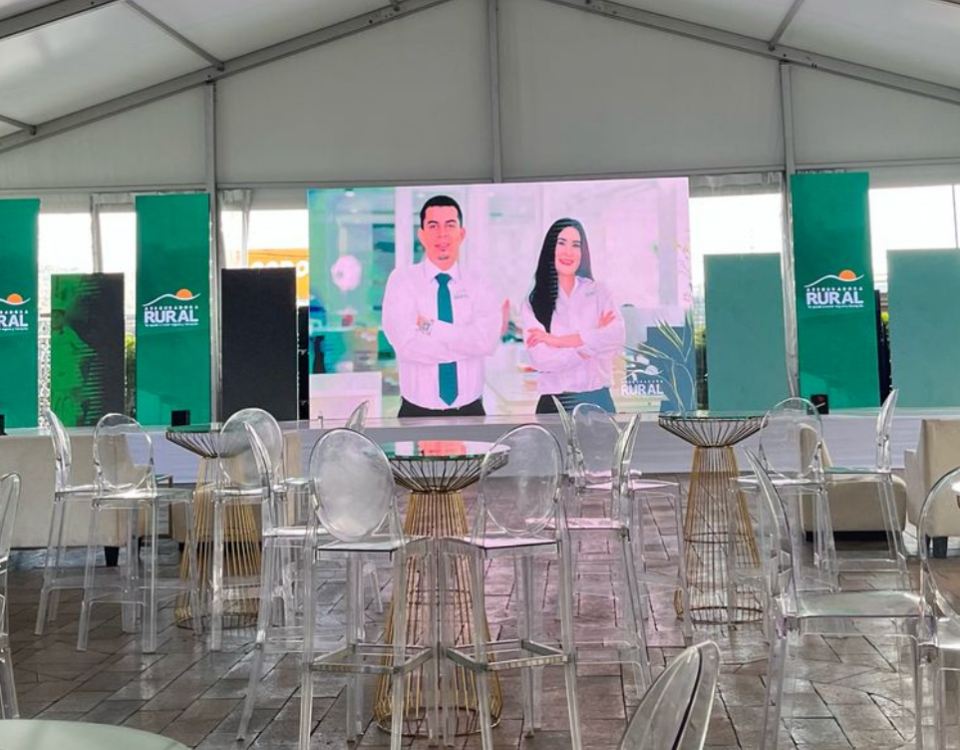 Montaje de evento corporativo de Caja Rural en Honduras con pantalla principal, mobiliario transparente y ambientación de marca