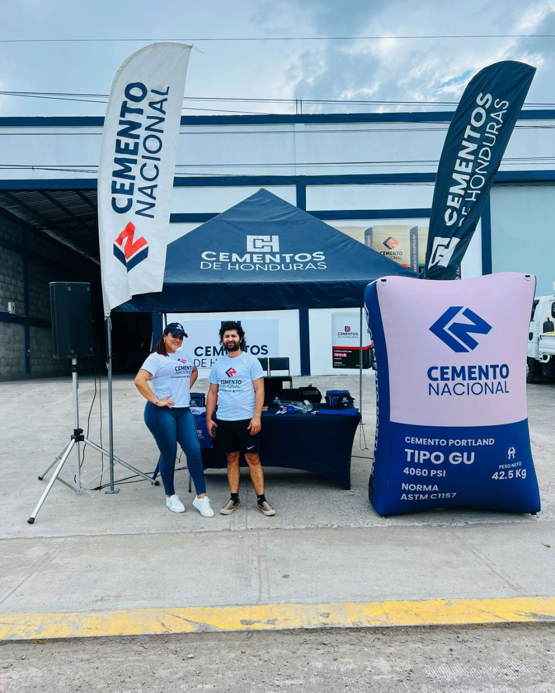 Stand promocional de cemento Argos con carpa, banderas publicitarias y equipo de apoyo frente a tienda.