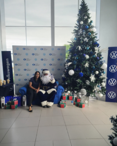 Persona sentada junto a árbol navideño con regalos en una experiencia BTL dentro de espacio corporativo decorado