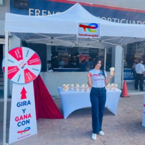 Promotora de TotalEnergies en evento BTL en Honduras con carpa promocional, ruleta interactiva y degustación de marca