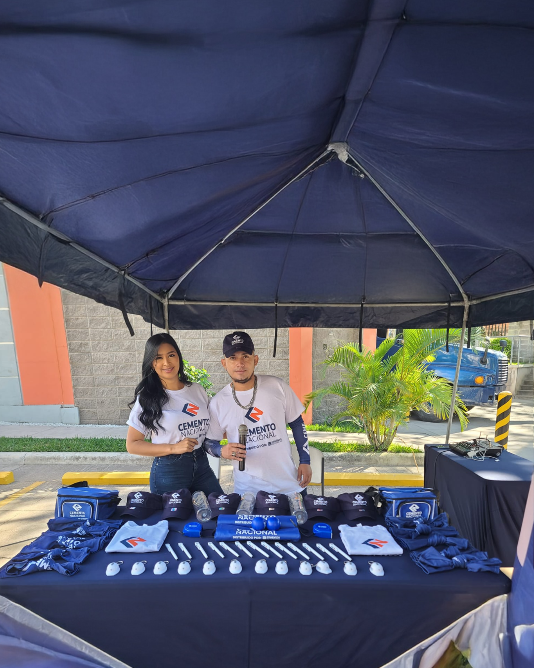 Hombre y mujer en stand de Cemento Nacional con mesa de exhibición y material promocional para activación de marca.