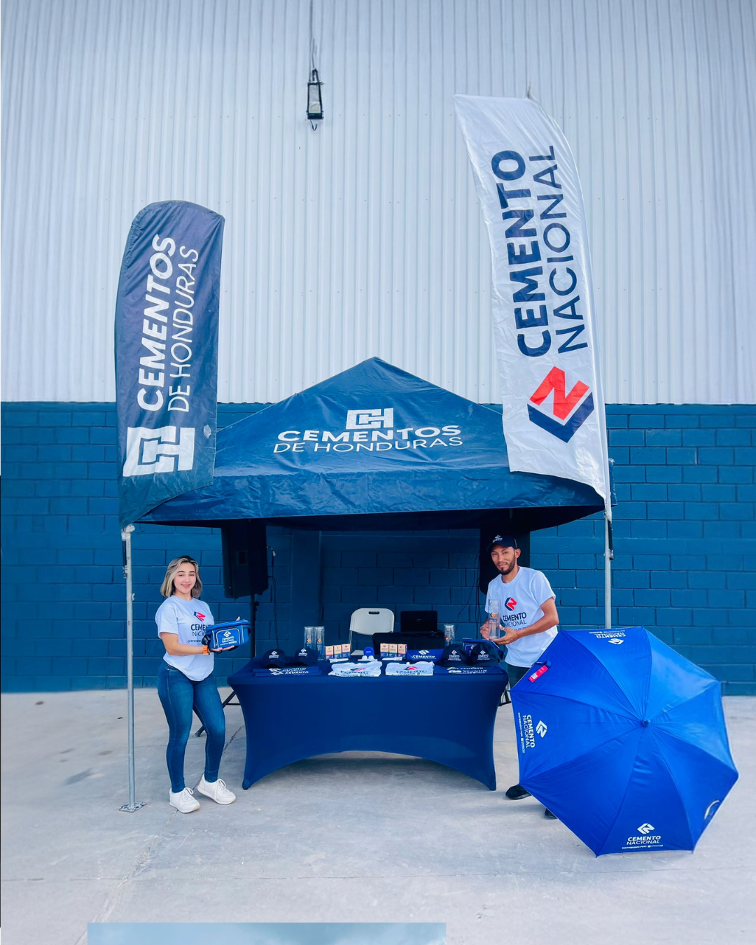 Equipo promocional de Cemento Nacional en stand exterior con carpa, bandera y sombrilla publicitaria.