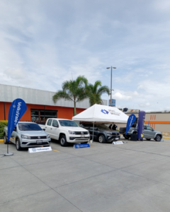 Publicidad presencial de autos en exterior con carpa promocional, vehículos y punto de exhibición de marca