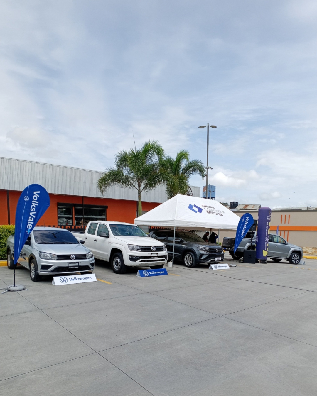 Publicidad presencial de autos en exterior con carpa promocional, vehículos y punto de exhibición de marca